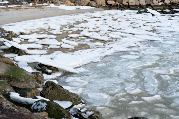 Landscape of a beach with snow on the ground at the sunset