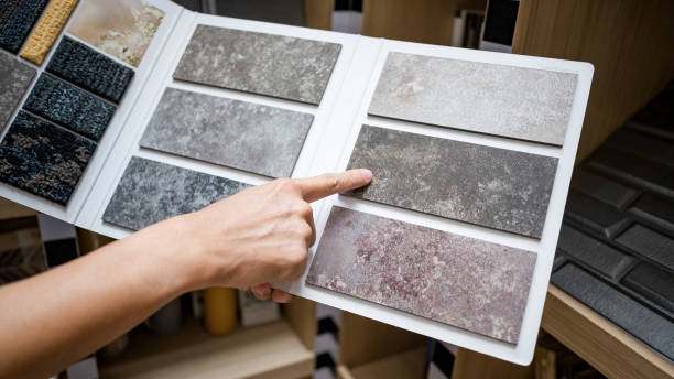 istock Flooring material design collection. Designer hand pointing at stone tile sample on display catalog. Customer choosing rough texture and pattern for floor finishing at home design store 2196284519