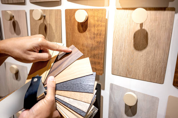 istock Designer hand pointing at sample of wood laminated from natural collection in material showroom. Choosing wooden veneer texture or MDF board swatch fan set for interior finishing or furniture design 2196284526
