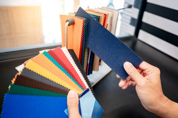 istock Fabric swatch material choice. Designer hand compares fabric sample pieces from color collection at interior decoration design store. Textile industry for furniture finishing decor 2196284665