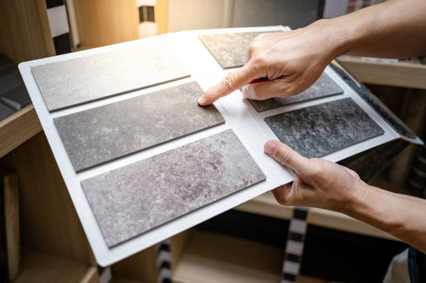 istock Flooring material design collection. Designer hand pointing at stone tile sample on display catalog. Customer choosing rough texture and pattern for floor finishing at home design store 2196284771