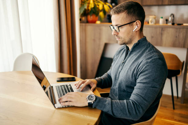 istock Side view of freelancer typing on laptop on kitchen table at home. 2196286140