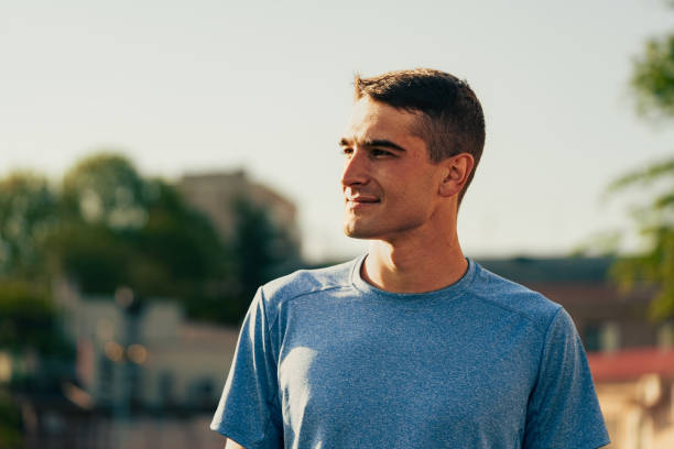 istock Young man enjoying a sunny day outdoors in a city environment while looking ahead with a smile 2196289814