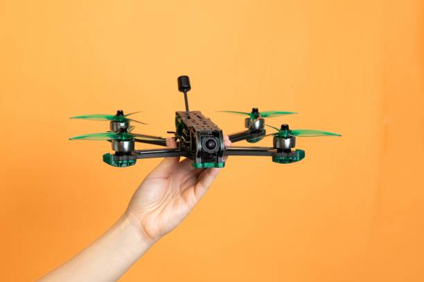 istock Professional modern drone with camera in hands isolated on orange background 2196294212