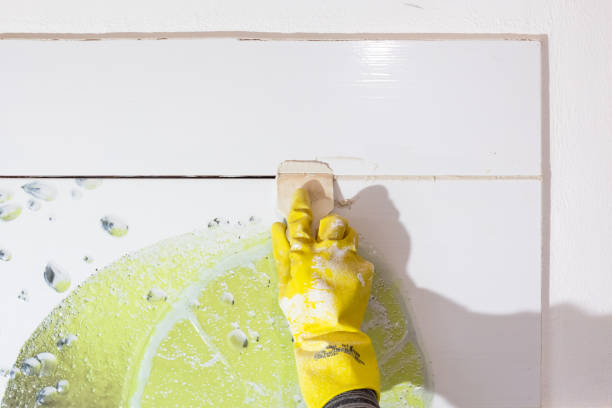 istock Laying ceramic tiles. The craftsman fills the tile joints with grout using a rubber spatula. 2196294377
