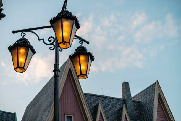 Three ornate lanterns cast a warm glow above a charming building. The soft light contrasts with the pastel hues of dusk, enhancing the historic atmosphere of the area.