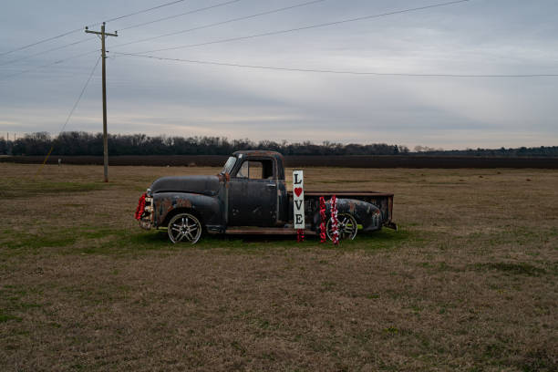 Photo of an old truck with love sign and red decorations in a field in the country.