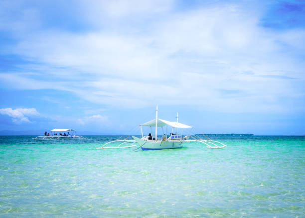 Alona beach, Bohol, Philippines, January 2025: Tourists on Alona Beach, Bohol. A tourist centre with boats moored off the beach. This is a well known spot for swimming.