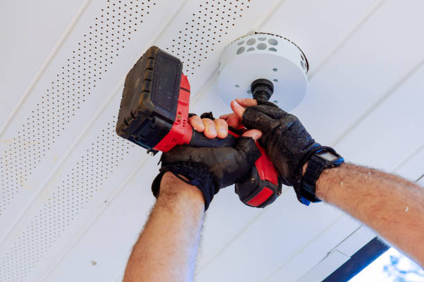 istock Using cordless drill with hole saw attachment, gloved hand cuts circular hole in white ceiling to install a new light fixture 2196308463