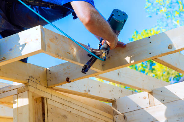 istock Carpenter uses nail gun to attach wooden beams while constructing a structure on a sunny day outdoors 2196308567
