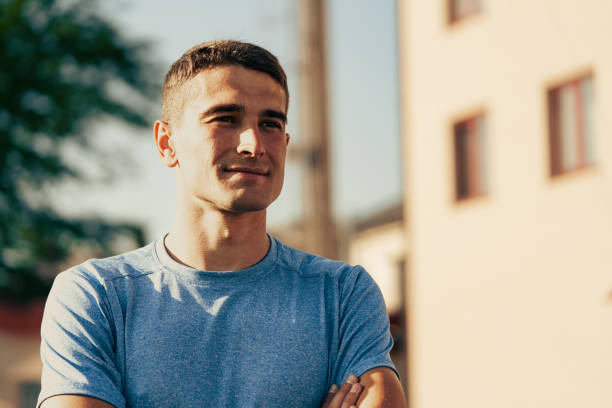 istock Young man smiling while standing against a building in a bright outdoor setting during daytime 2196324467