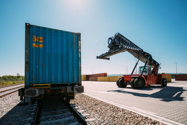 istock Industrial Reach Stacker Near Blue Shipping Container on a Sunny Day 2196324569