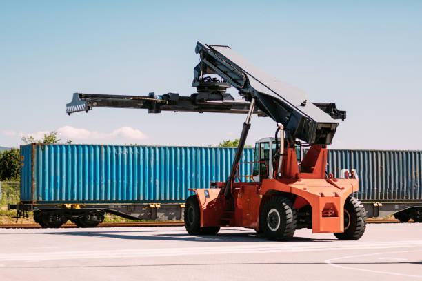 istock Industrial Reach Stacker Near Blue Shipping Container on a Sunny Day 2196324586