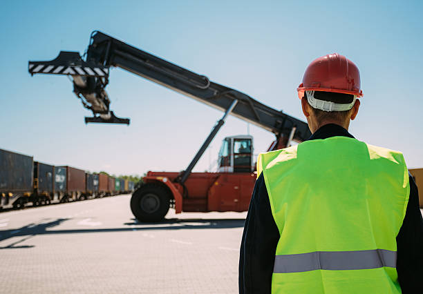 istock Worker Observing Cargo Handling With Heavy Equipment in a Shipping Terminal 2196324607