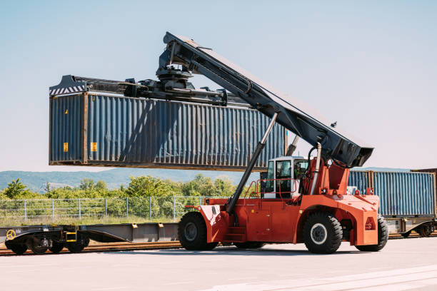 istock Large Red Crane Loader Lifting Shipping Container onto Rail Transport System 2196324616