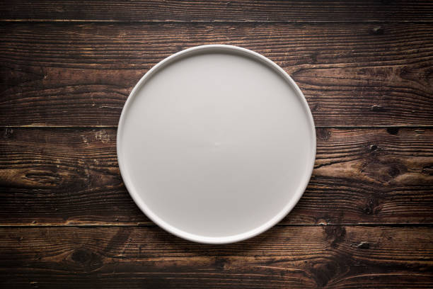 istock Top view of empty ceramic white plate on wooden table 2196325004