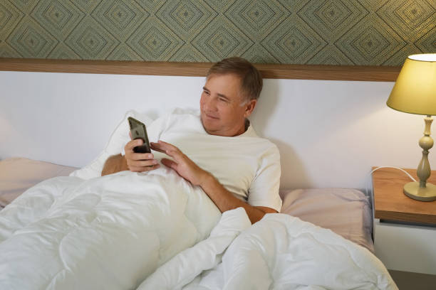 istock man with a phone lies in bed and smiles. 2196325794