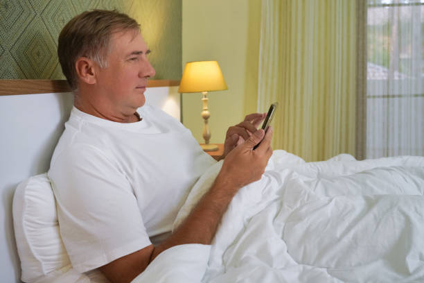 istock man with a phone lies in bed and smiles. 2196325796