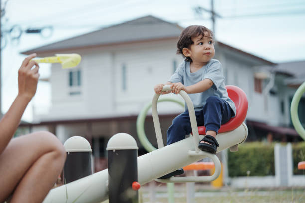 Cute Asian boy having fun while playing on the playground on sunny day. Outdoor activity.