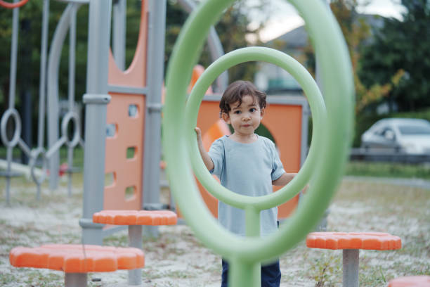 istock Cute Asian boy having fun while playing on the playground on sunny day. Outdoor activity. 2196326332