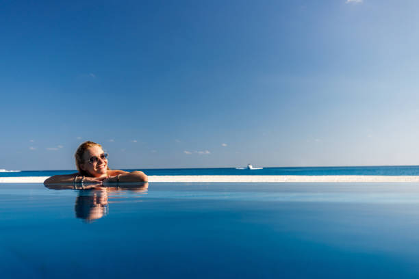 istock Happy woman enjoying by the infinity pool on the beach. 2196332787