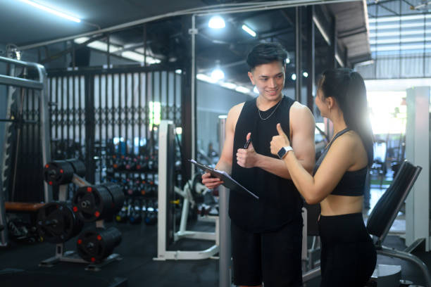 istock Fitness trainer and a female client sitting on the gym floor discussing progress and workout plans 2196332921