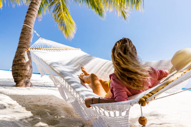 istock Back view of a woman relaxing in hammock on the beach. 2196333690