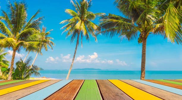 istock empty multicolor wood table and tropical beach with coconut palm tree in background. for place summer product ,food or beverage. 2196337358