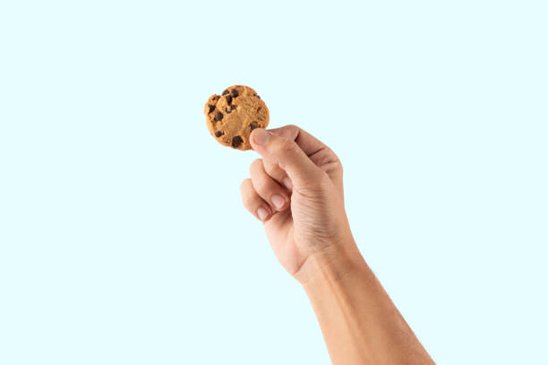 istock Male hand holding a cookie isolated on cyan background 2196338062