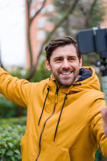 istock Tourist wearing yellow jacket taking selfie with smartphone on tripod 2196341607
