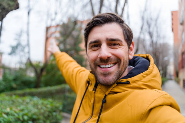 istock Happy man taking selfie and pointing while walking in the city during winter 2196341620