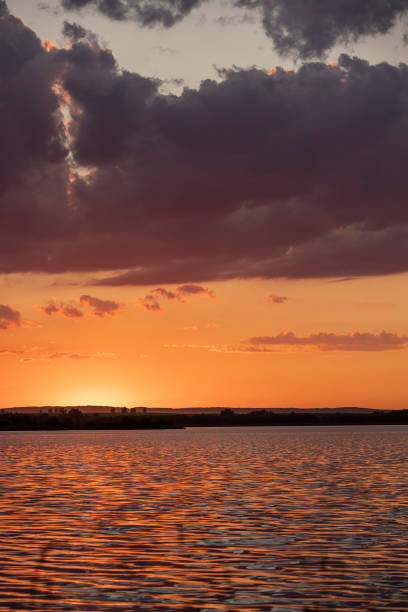 river at sunset, the colorful sky and clouds are reflected on the river, a beautiful summer landscape on the lake at sunset with clouds and rays of the sun