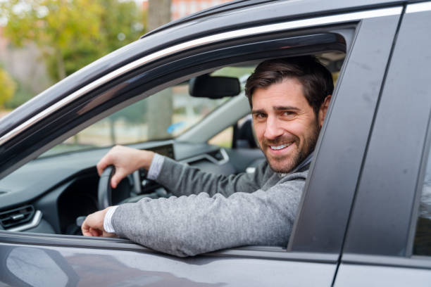 istock Businessman driving car and smiling at camera 2196341902