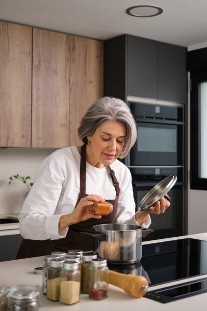 istock Mature chef adding spices to a pot in the kitchen 2196343740
