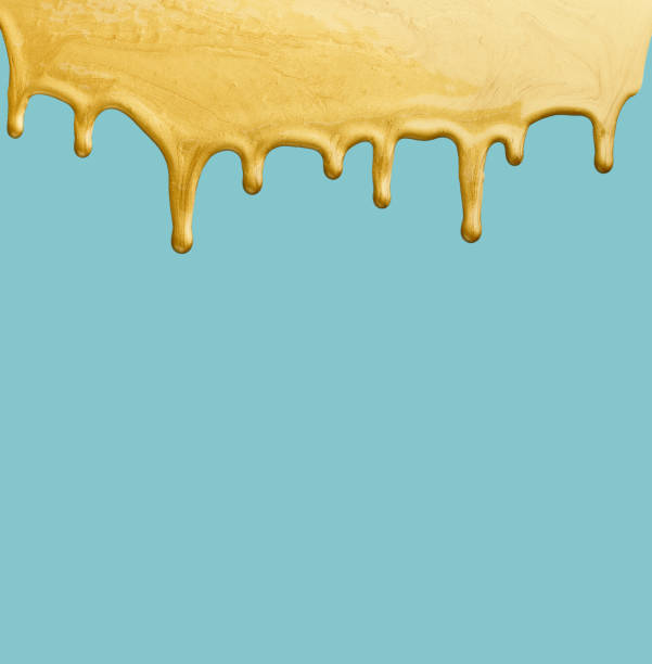 istock Dripping Gold Paint Against a Light Blue Background in an Artistic Setting 2196344040
