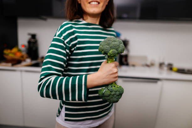 istock Woman holds exercise with broccoli dumbbell in kitchen 2196346997