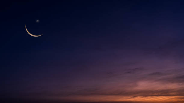 istock Crescent moon on twilight sky in evening vertical with colorful sunlight after sundown, symbol Islamic religion Ramadan, Dusk sky space backgrounds well for Arabic text present Eid al Adha, Eid ul fitr. 2196348319