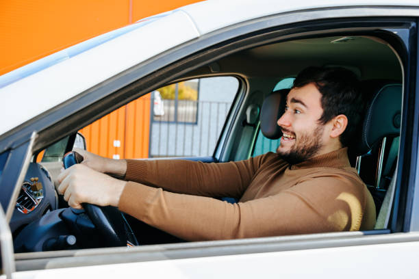 istock A young guy driver holds the steering wheel with his hands, looking ahead of him laughing. 2196348664