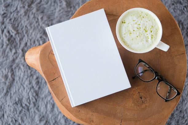 blank book mockup on white coffee table with green matcha tea near window