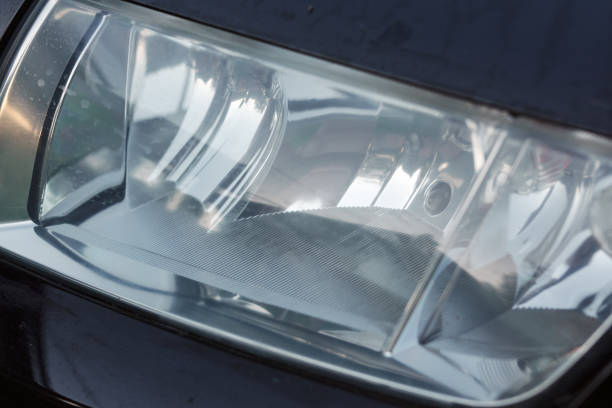 Polished car headlight in black car body, street photo