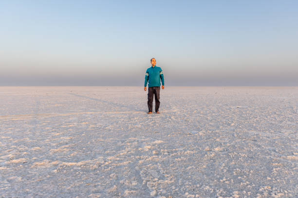 man enjoying at remote white salt desert with bright orange sky at morning from low angle image is taken at dhordo kutch white rann gujrat india.