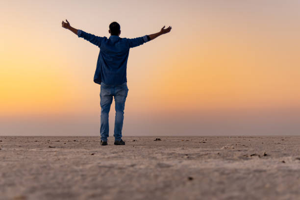 istock man enjoying at remote white salt desert with bright orange sky at morning from low angle 2196353800