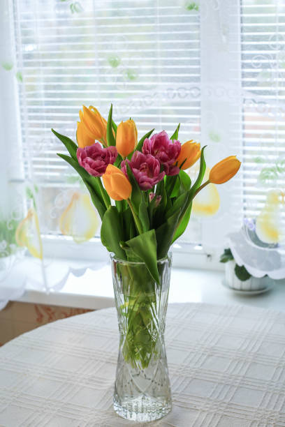 istock A vase with a beautiful purple and yellow tulips on a white round table 2196354059