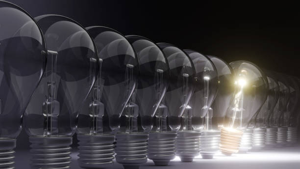 istock Light bulbs lined up, one glowing distinctly, symbolize an idea and the career concept of standing out. 2196358879