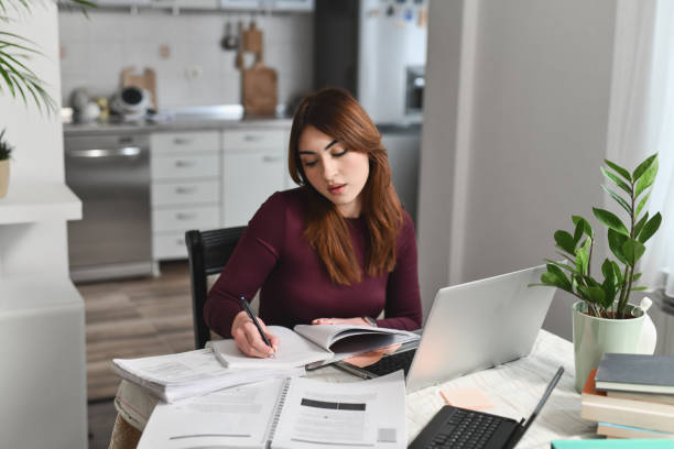 istock Dedicated Female Student Writing University Homework Using Laptop and Books 2196359166