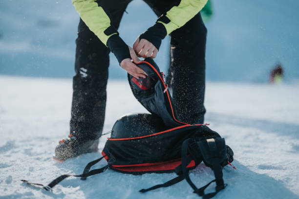 Person organizing equipment in backpack on a snowy winter day.