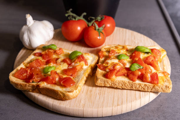 istock Tomato and Cheese Toast with Fresh Basil on Wooden Board 2196361565
