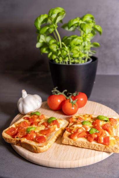 istock Tomato and Cheese Toast with Fresh Basil on Wooden Board 2196361590