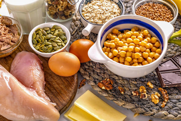 Serotonin rich foods like chicken fillet, chickpeas, pumpkin seeds, bananas, yogurt, tuna, eggs, dark chocolate and walnuts top view. Healthy eating concept