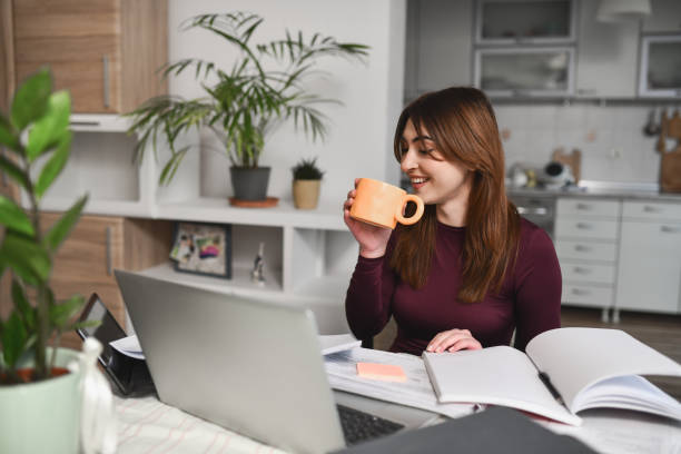 istock Beautiful Female Student Having Virtual Class on Laptop Drinking Coffee And Enjoying 2196362156
